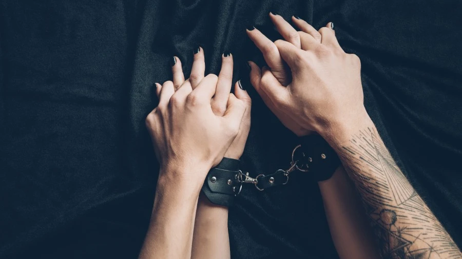 Masculine male hands holding his girlfriend's handcuffed hands