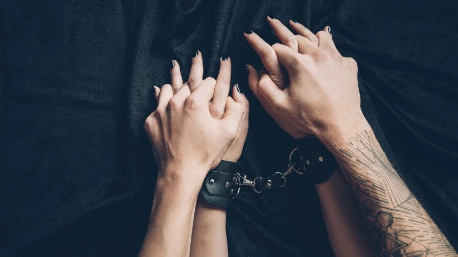 Dominant man holding his partners handcuffed hands