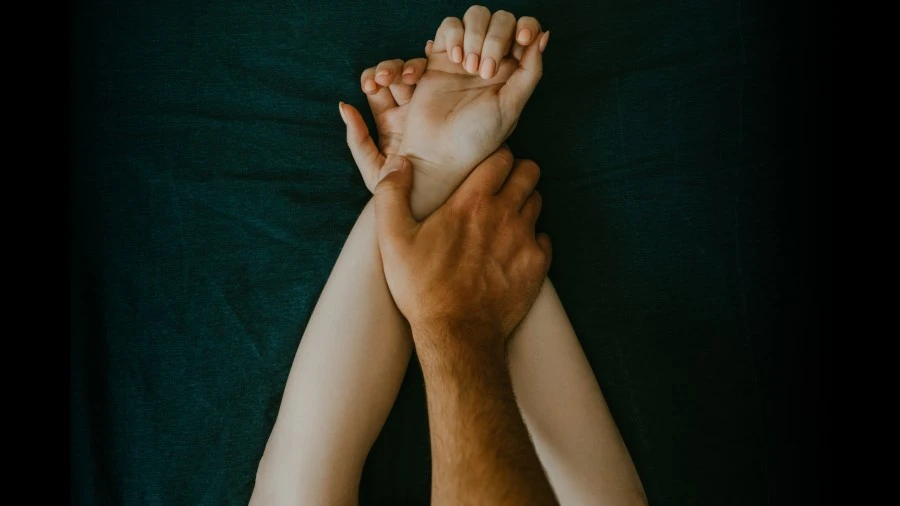 Photo of man's hands pinning down his girlfriend's arms