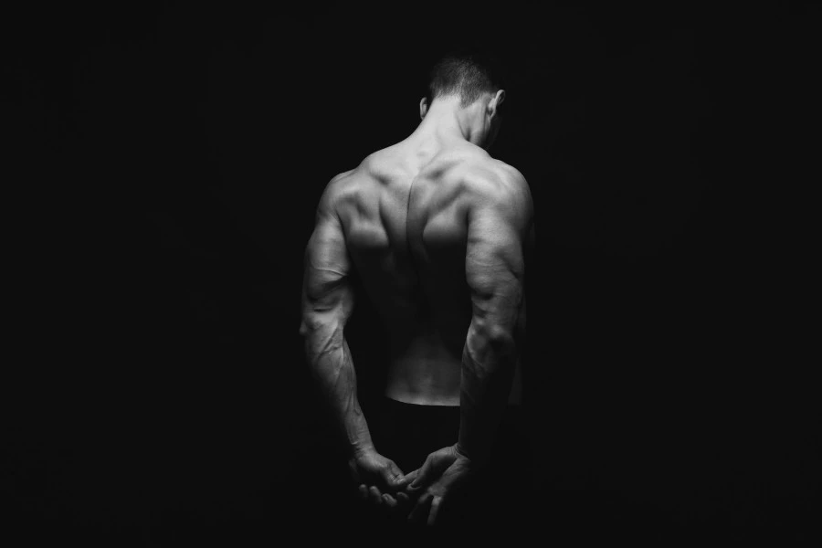 A muscular man stretching his back, hands behind his back